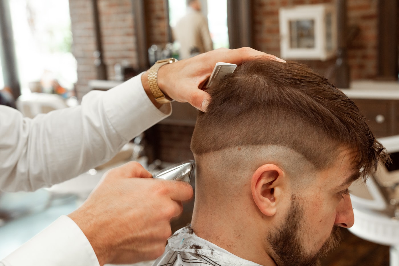 A barber carefully finishing a client's fade in the shop