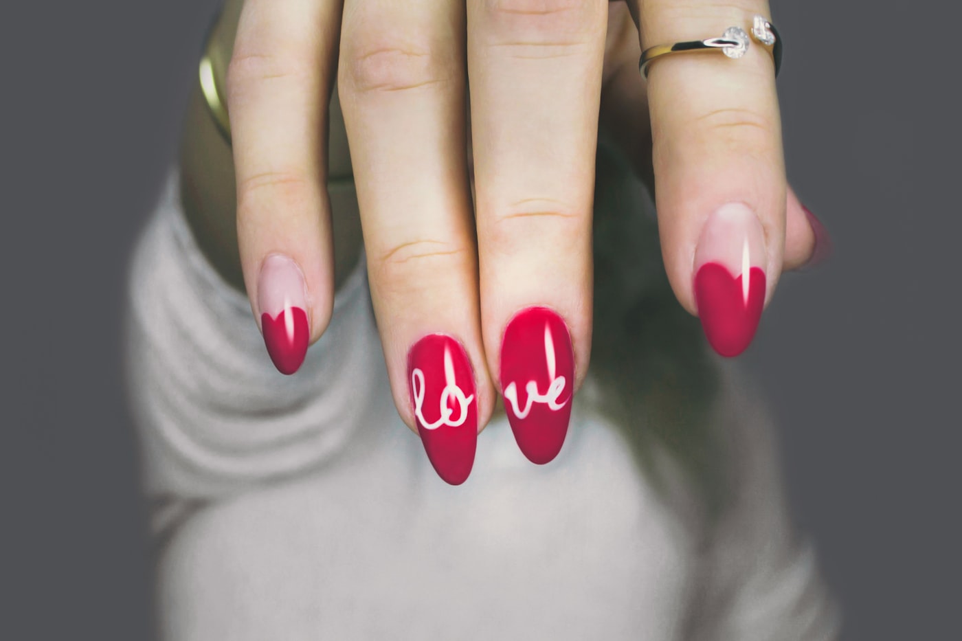 Close-up of vivid red manicured nails with hand-painted lettering